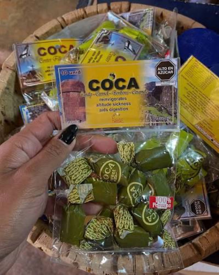 Pacotes de balinhas de coca vendidos numa cesta de vime, com selo de alto teor de açúcar na embalagem.
