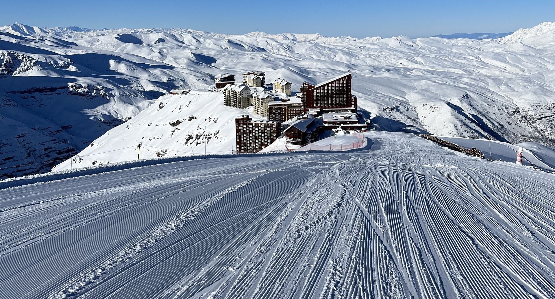 Pistas de neve e o complexo hoteleiro do Valle Nevado sob céu azul.