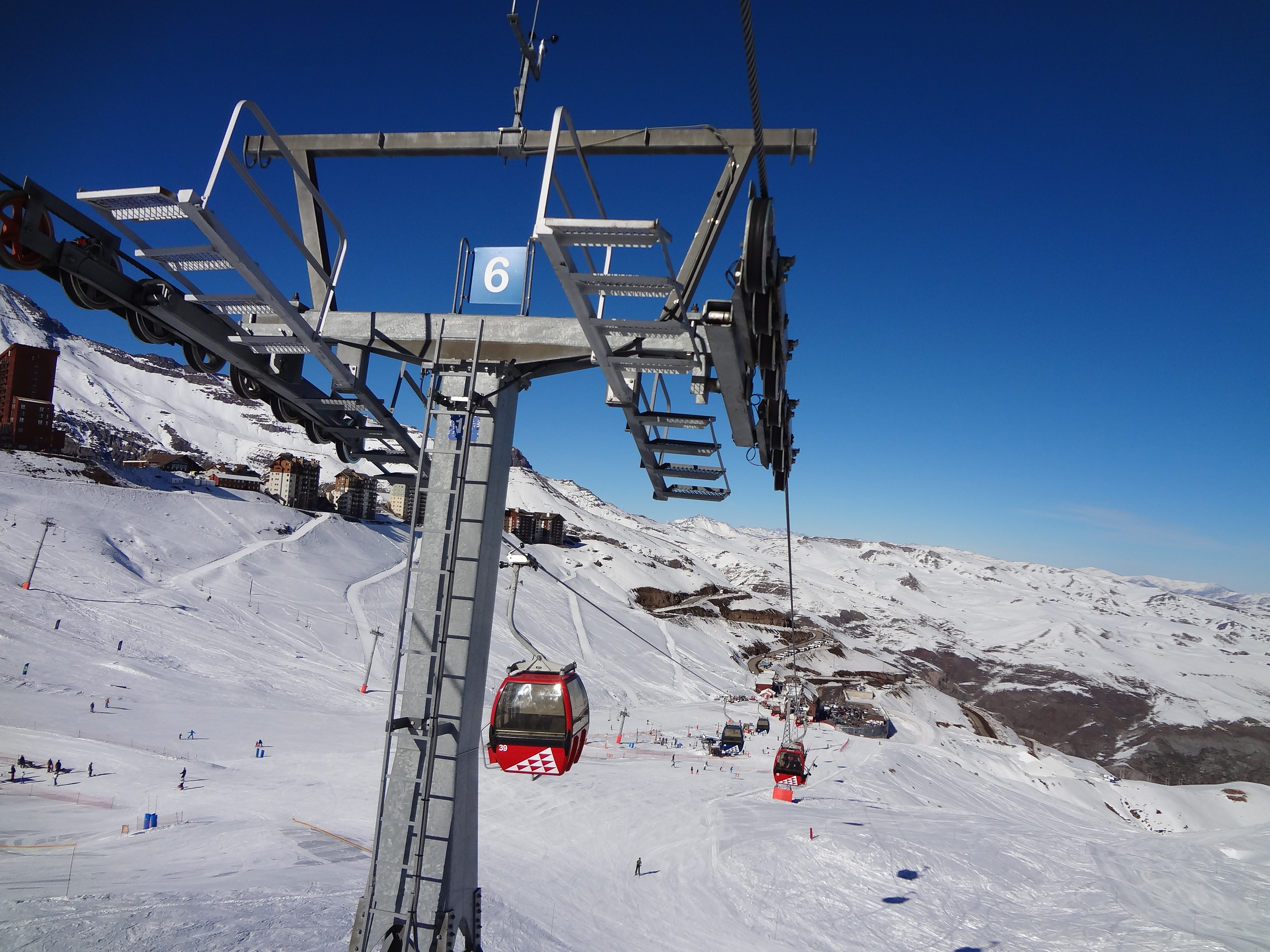 Gôndolas vermelhas em movimento subindo a encosta do Valle Nevado.