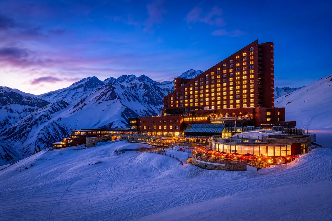 O complexo de hotéis do Valle Nevado iluminado ao entardecer, cercado de neve nos Andes.